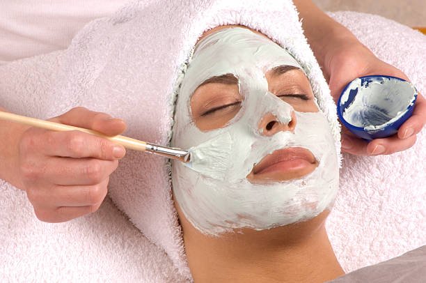 Skincare specialist performing a deep pore cleanse with steam and towel wrap in a luxury facial room